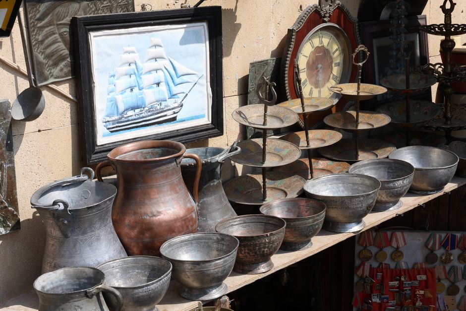 Antique shop display featuring vintage metalware, a ship pai