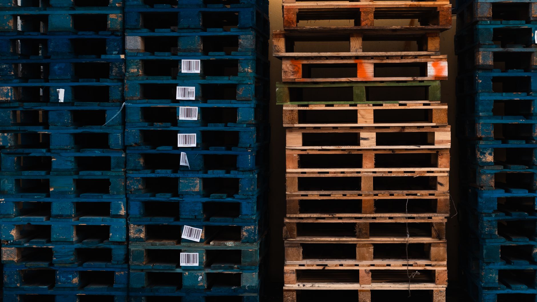 Close-up of stacked wooden pallets with barcodes in a warehouse environment.