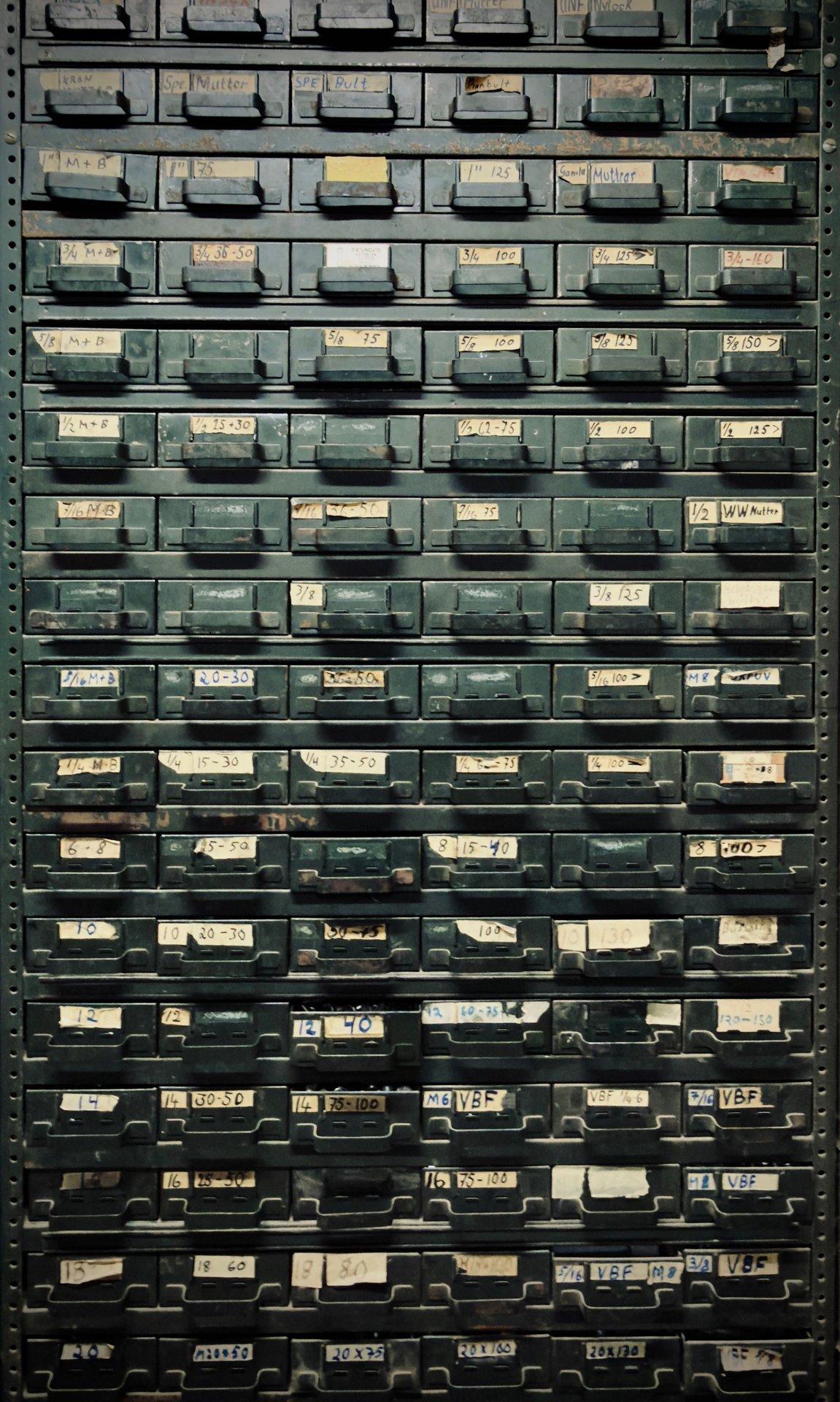 A vintage metal cabinet with labeled drawers, ideal for indu