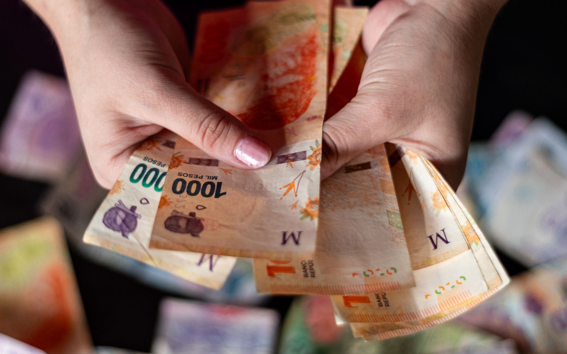 Detailed view of hands holding Argentine peso banknotes, sym