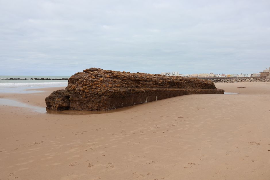 A medieval city wall on a sandy beach in Cádiz, Spain, with