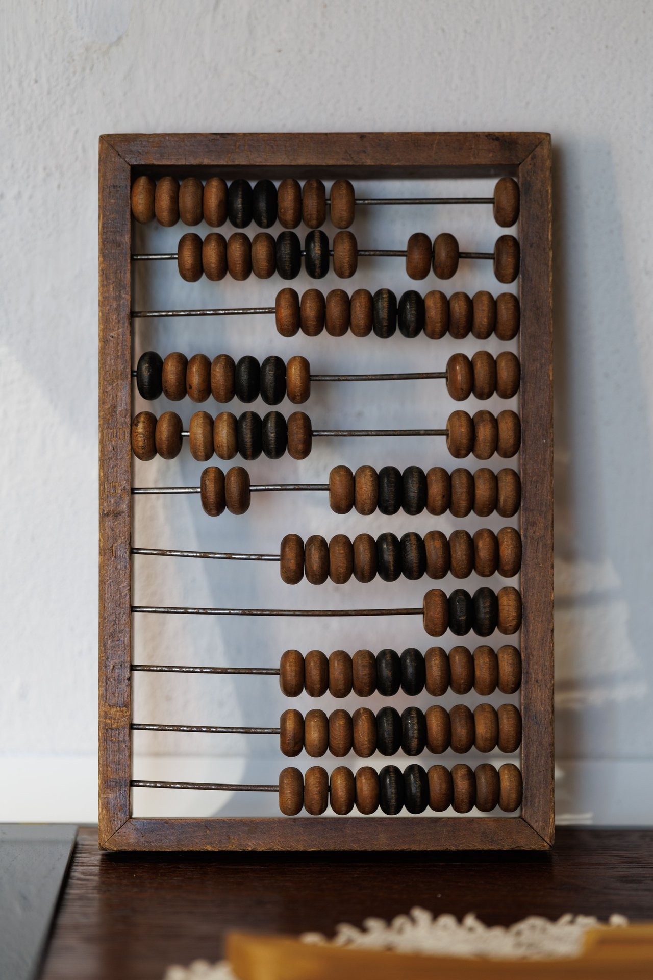 Vintage wooden abacus with brown and black beads on a white