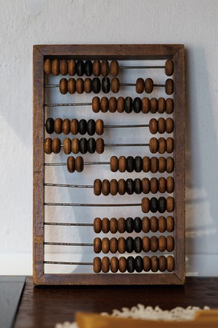 Vintage wooden abacus with brown and black beads on a white