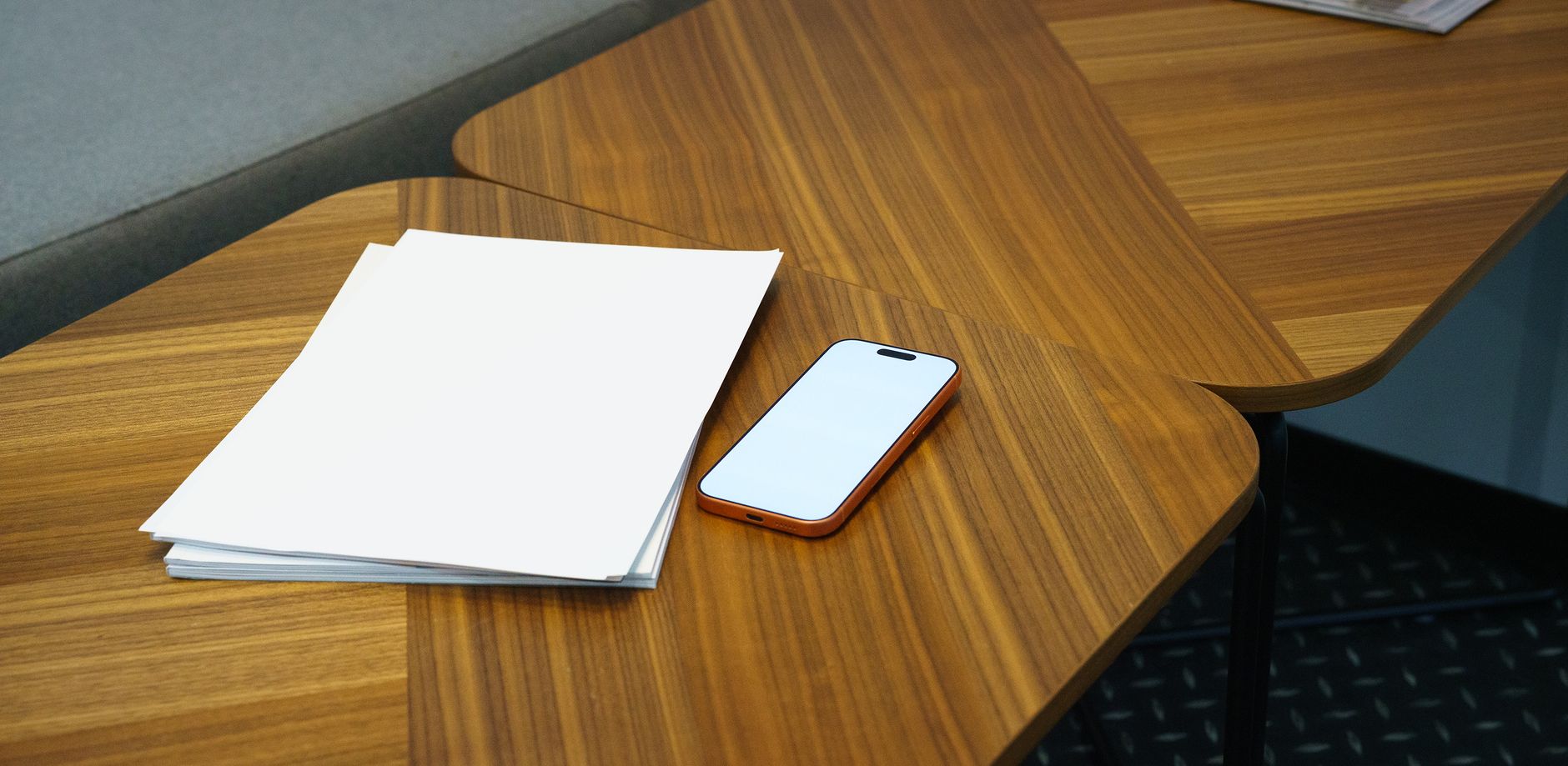 A tidy office desk with a smartphone and a stack of papers,