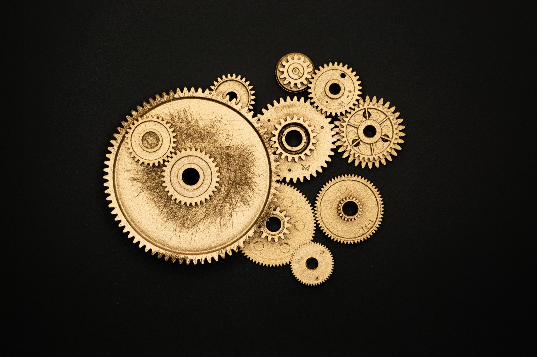 Close-up of golden cogs and gears arranged on a black backgr