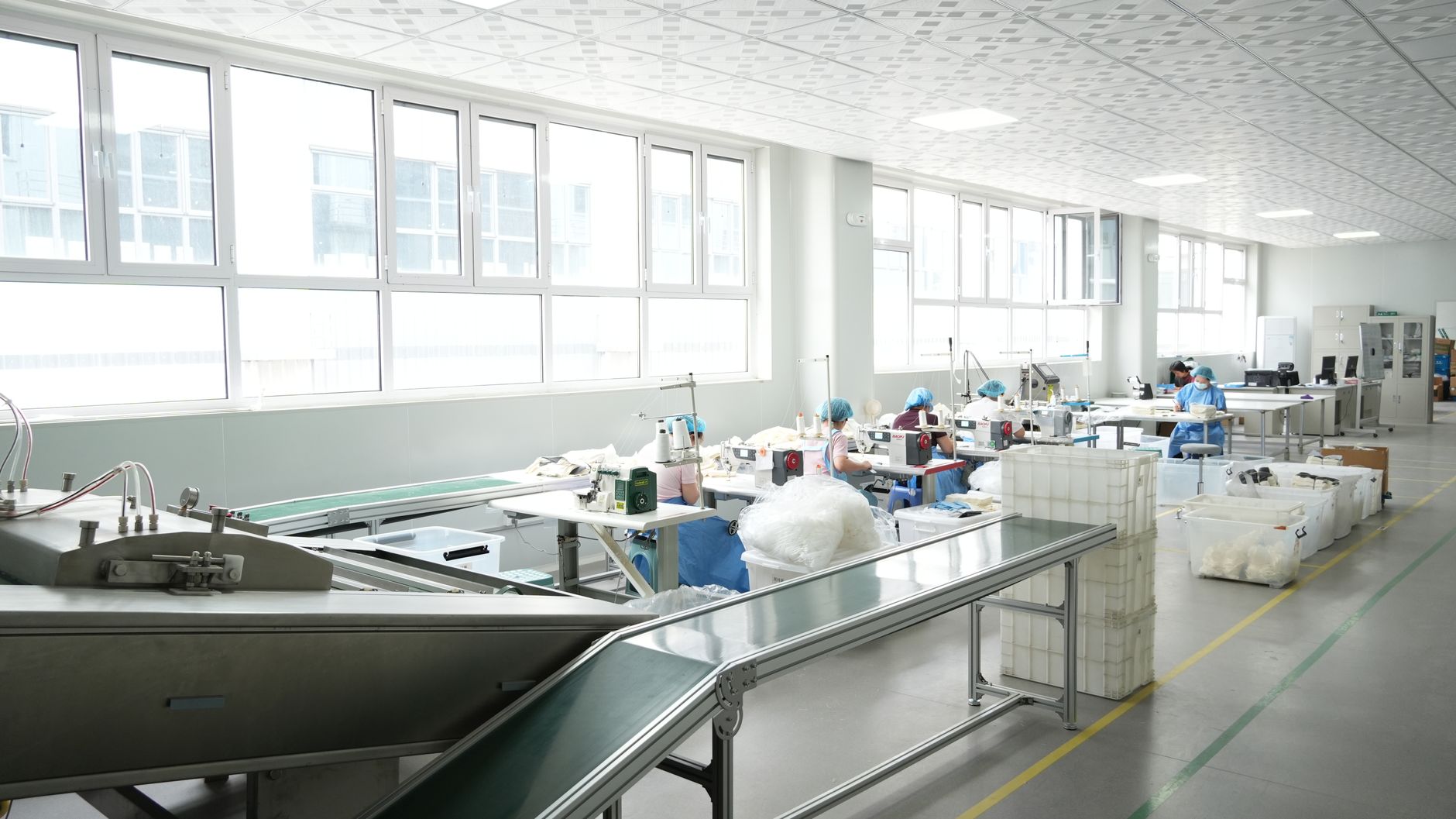 A modern factory interior with workers operating sewing mach