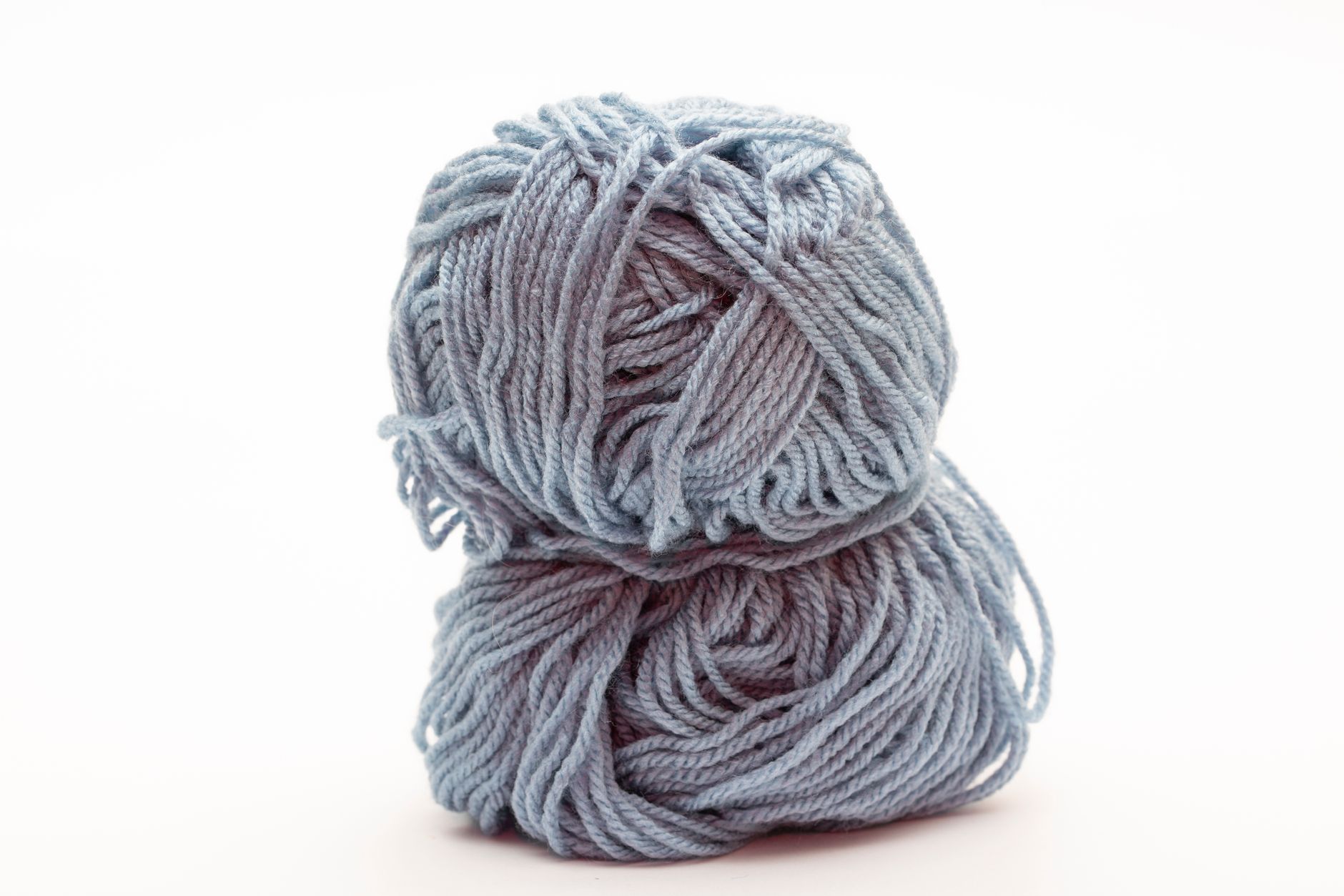 Two blue yarn skeins stacked on a white background, perfect