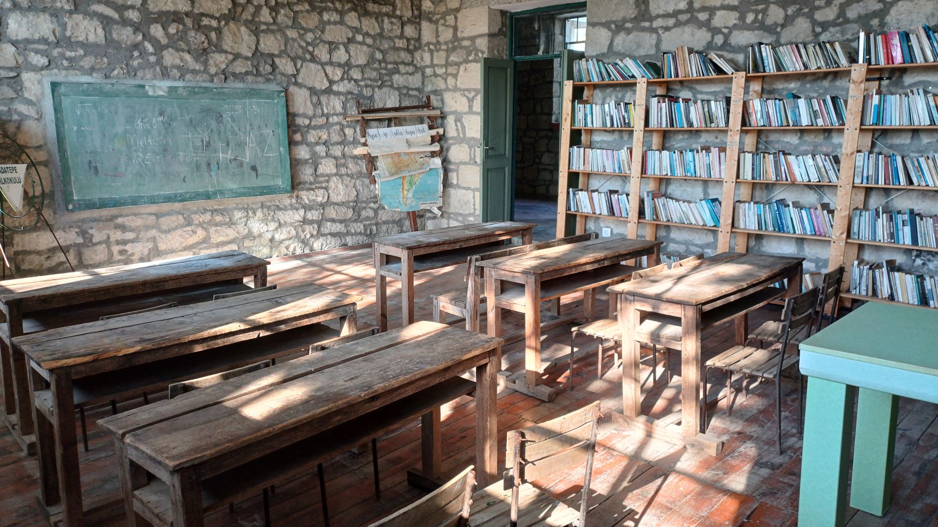 Vintage classroom with wooden desks, blackboard, and bookshe