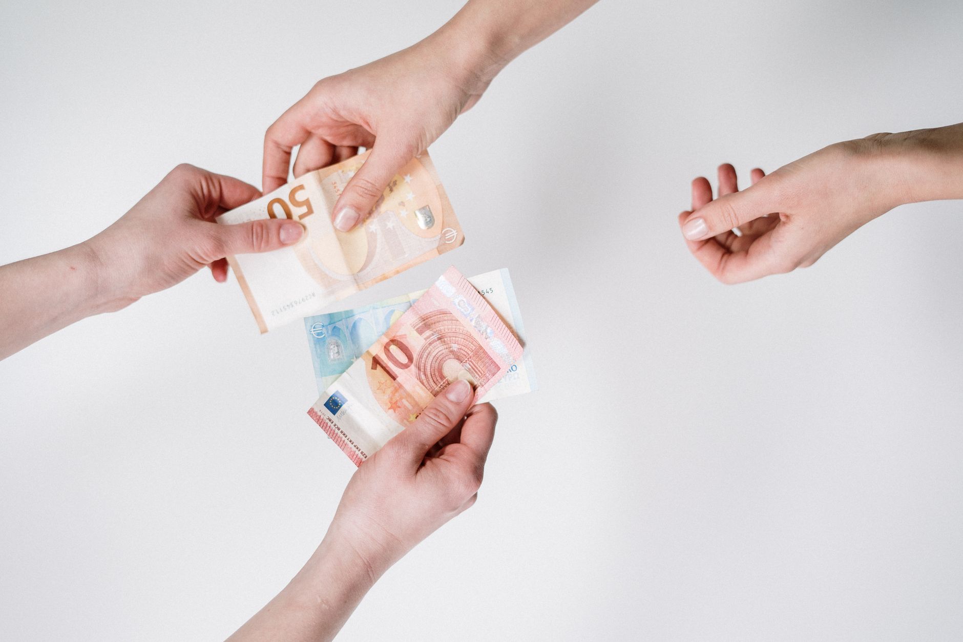 Close-up of hands exchanging euro banknotes, symbolizing cur