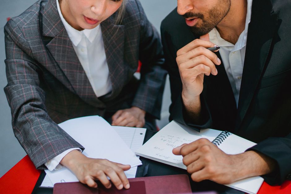 Two business professionals discussing plans with notebooks a