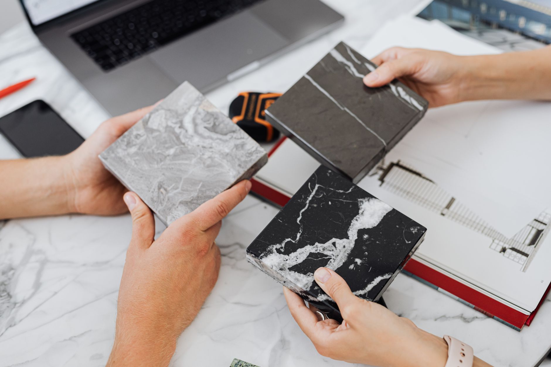 Two architects selecting marble tile samples on a desk in an