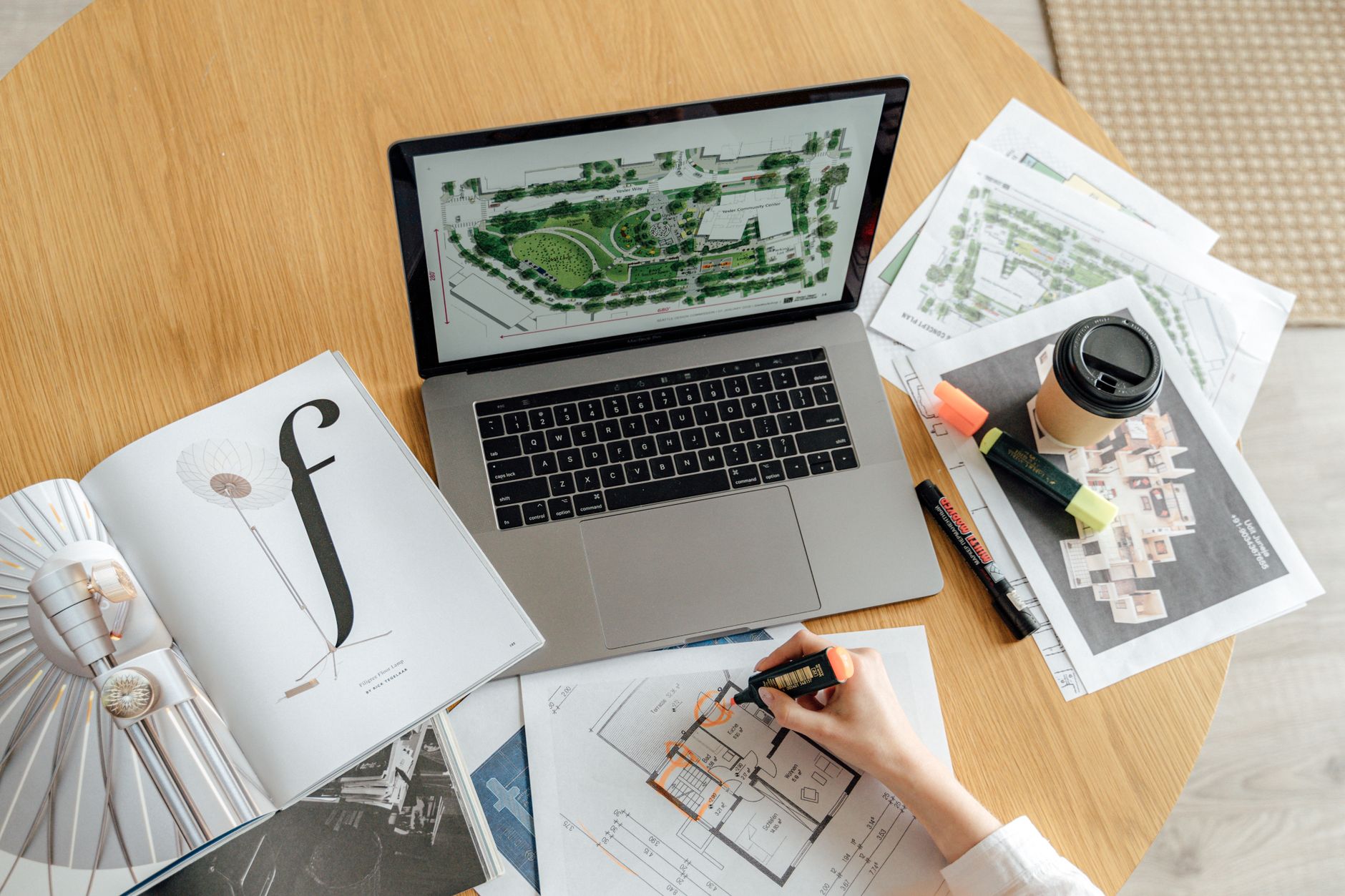 Top view of an architecture workspace with a laptop, blueprints, and notes.