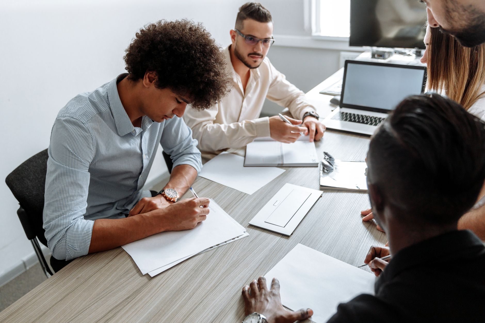 A multi-ethnic group working together at a desk with laptops