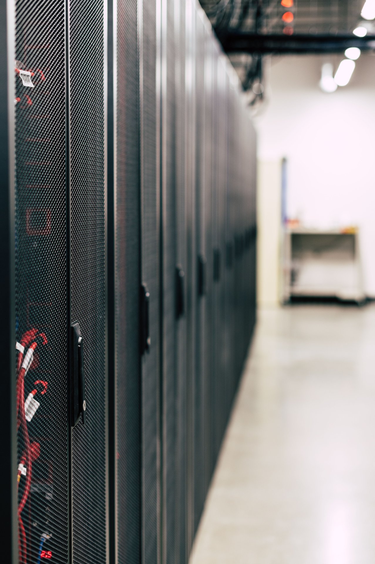 Metal black cabinets with servers inside with red wires conn