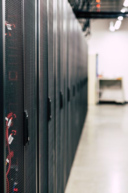 Metal black cabinets with servers inside with red wires conn