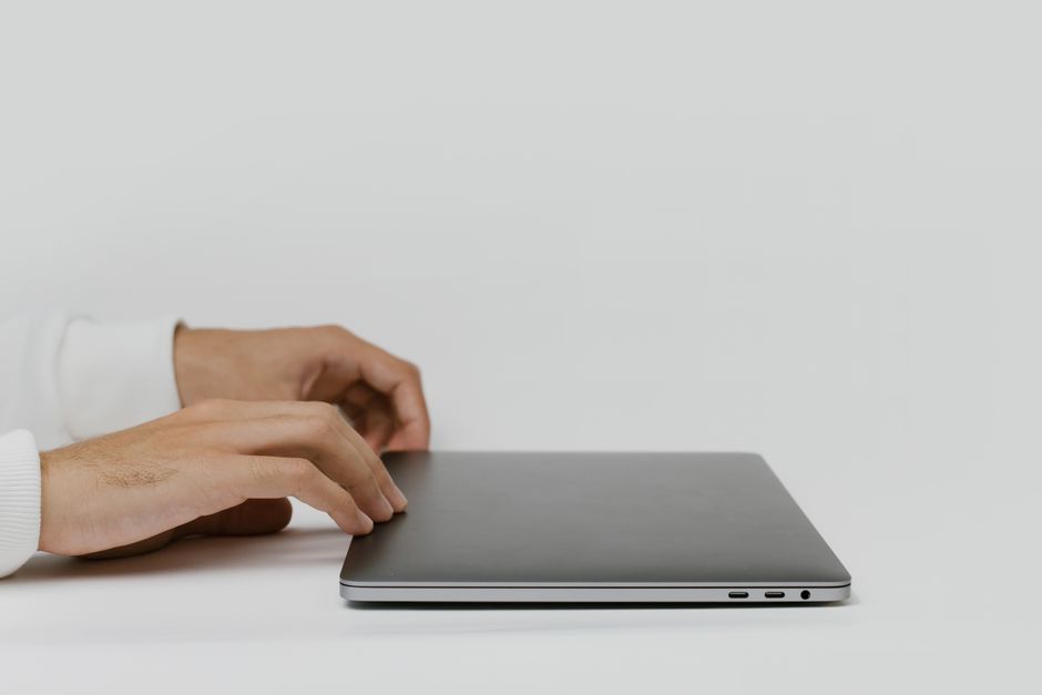 Hands preparing to open a closed laptop on a minimalist desk