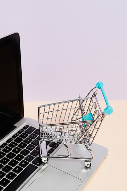 Mini shopping cart on a laptop symbolizes online shopping an