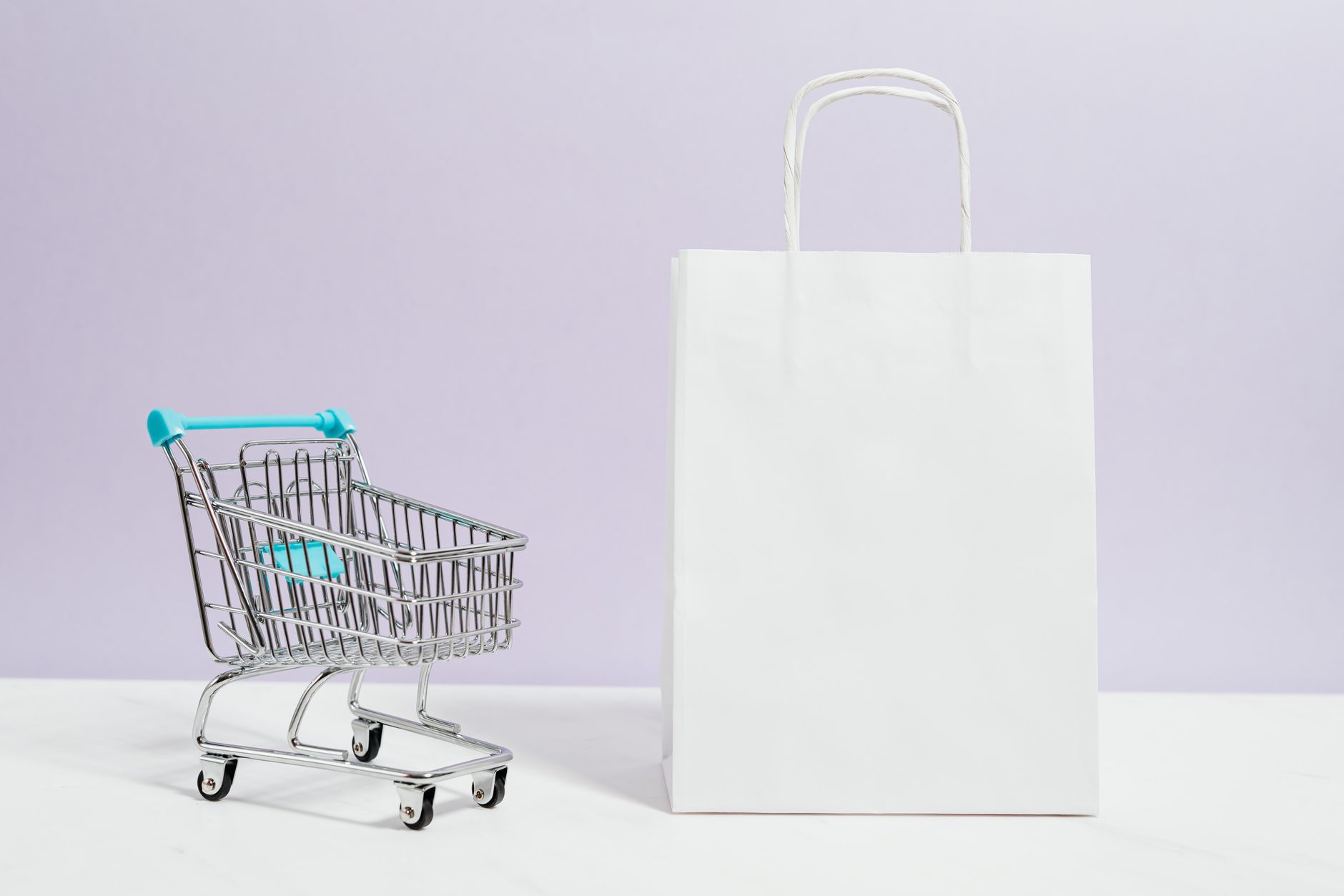Minimalist image of a white shopping bag and mini cart on a