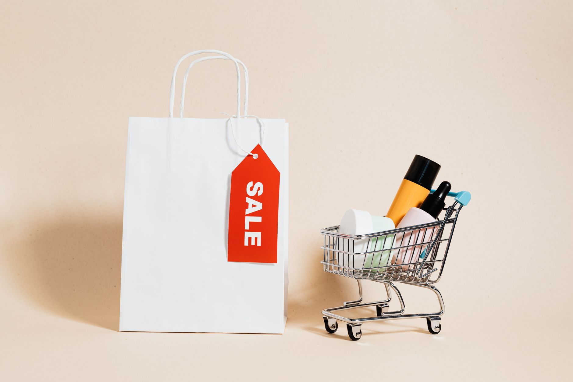 White shopping bag with red sale tag and mini shopping cart
