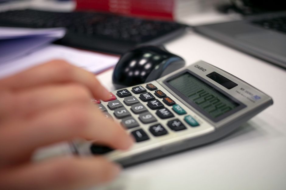 Close-up of a hand using a calculator on an office desk for