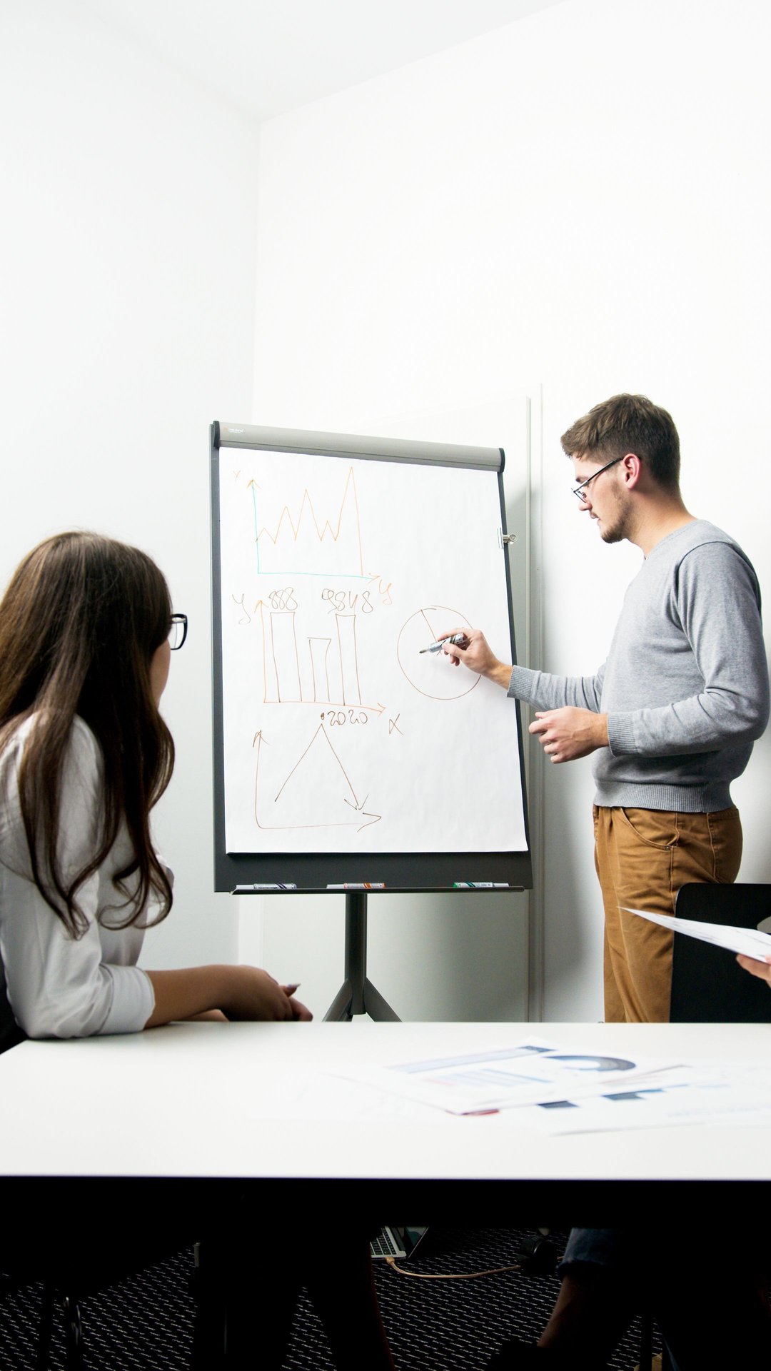 A businessperson giving a presentation with charts in a modern office environment.