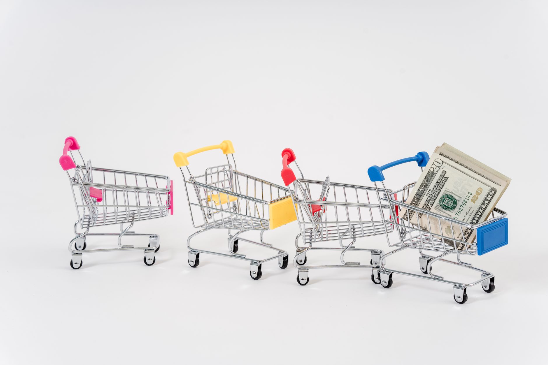 Miniature shopping carts in bright colors with dollar bills