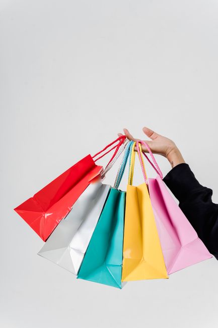 A hand holding colorful shopping bags against a white backgr