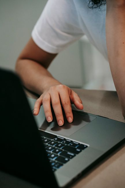 Crop anonymous female freelancer browsing laptop placed on t