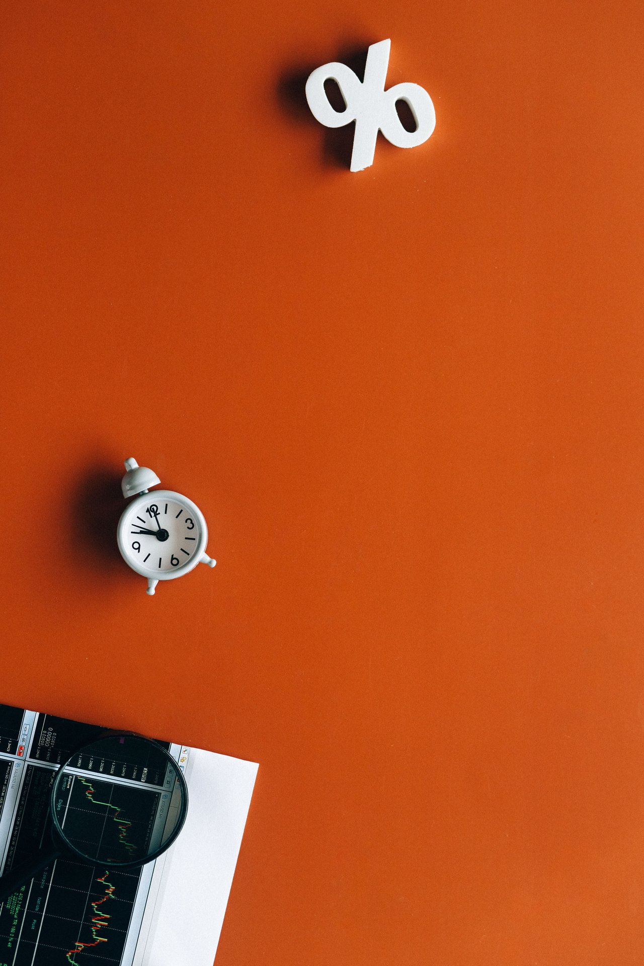 An arrangement featuring a clock, percentage symbol, and financial charts conveying time and finance concepts.