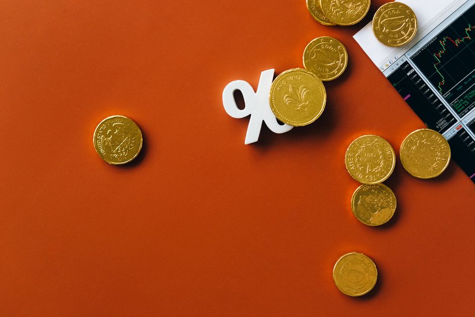 Gold coins scattered with a stock market graph and a percent