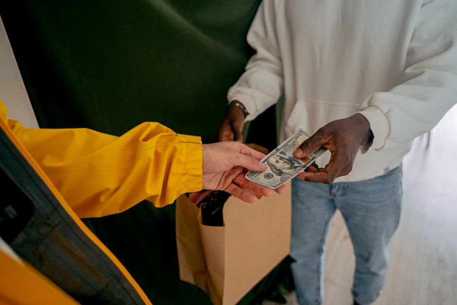 A close-up of a cash transaction between two adults, highlig