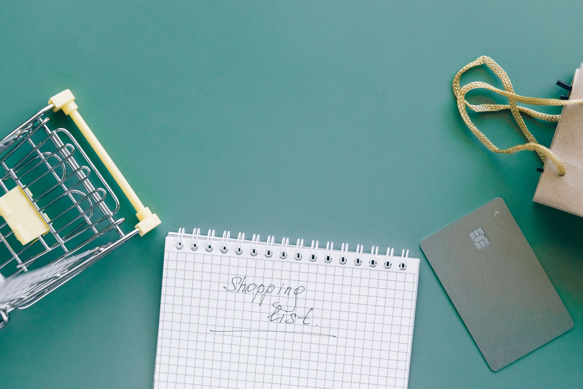 A top-down view of a shopping cart, list, card, and bag on a