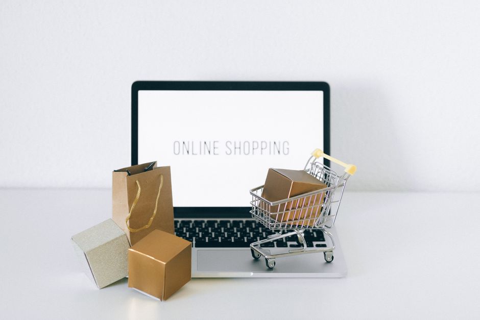 Laptop displaying online shopping with boxes and cart, repre