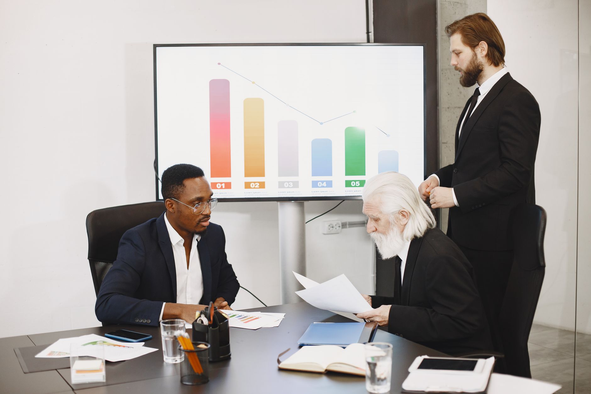Three businessmen discussing financial data in a modern offi