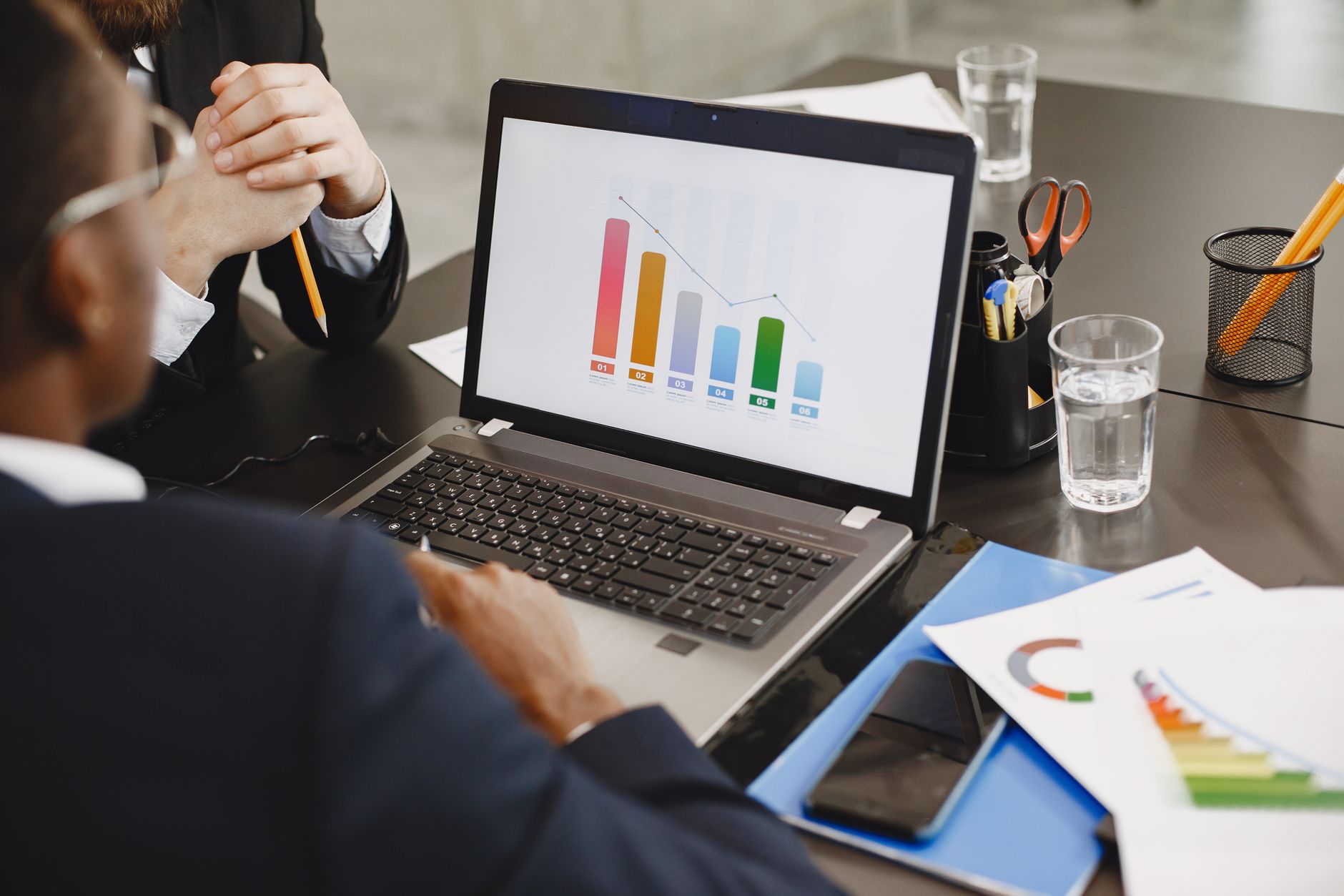 Two professionals analyzing a business graph on a laptop dur
