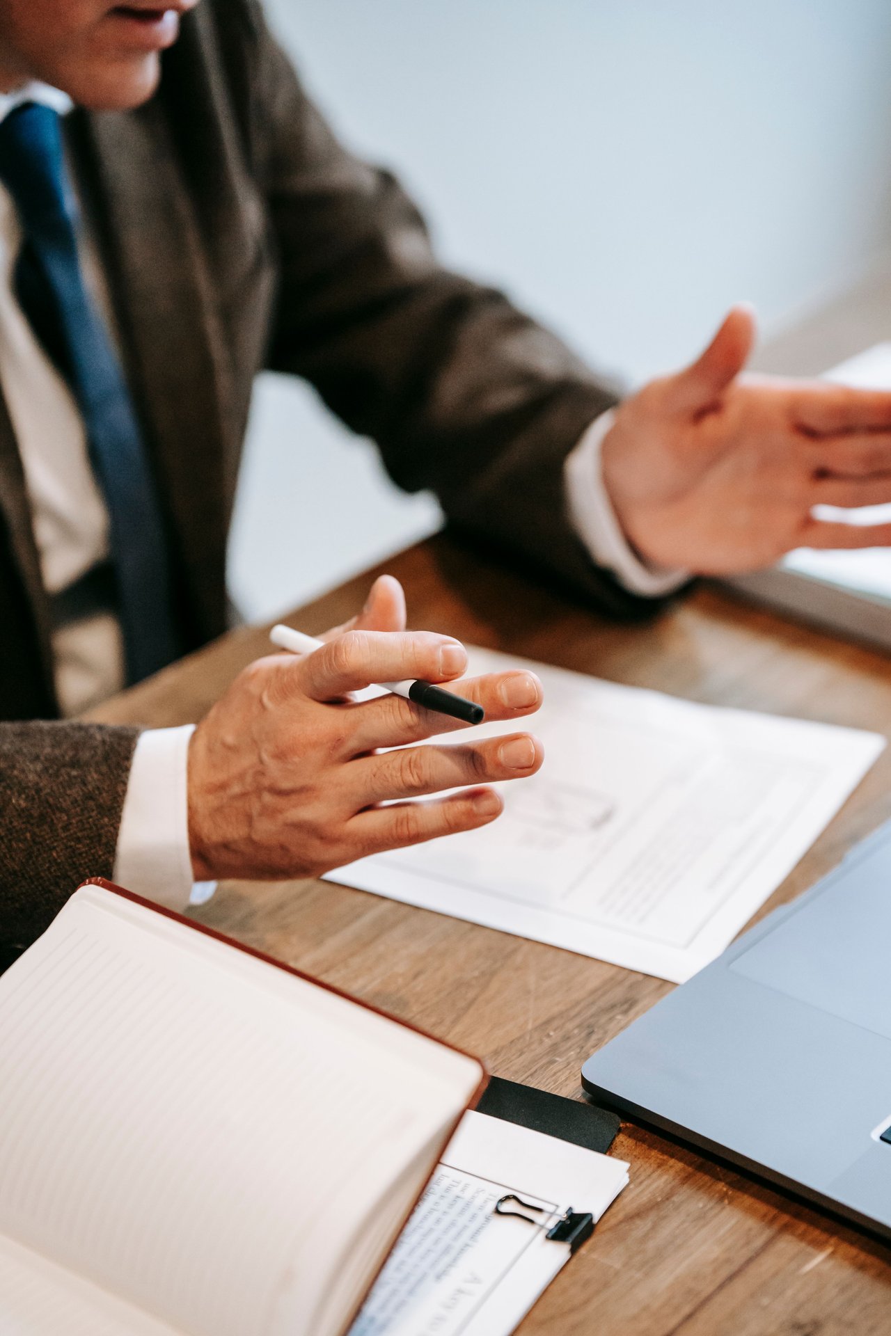 Professional discussing documents over a wooden table in an office setting.