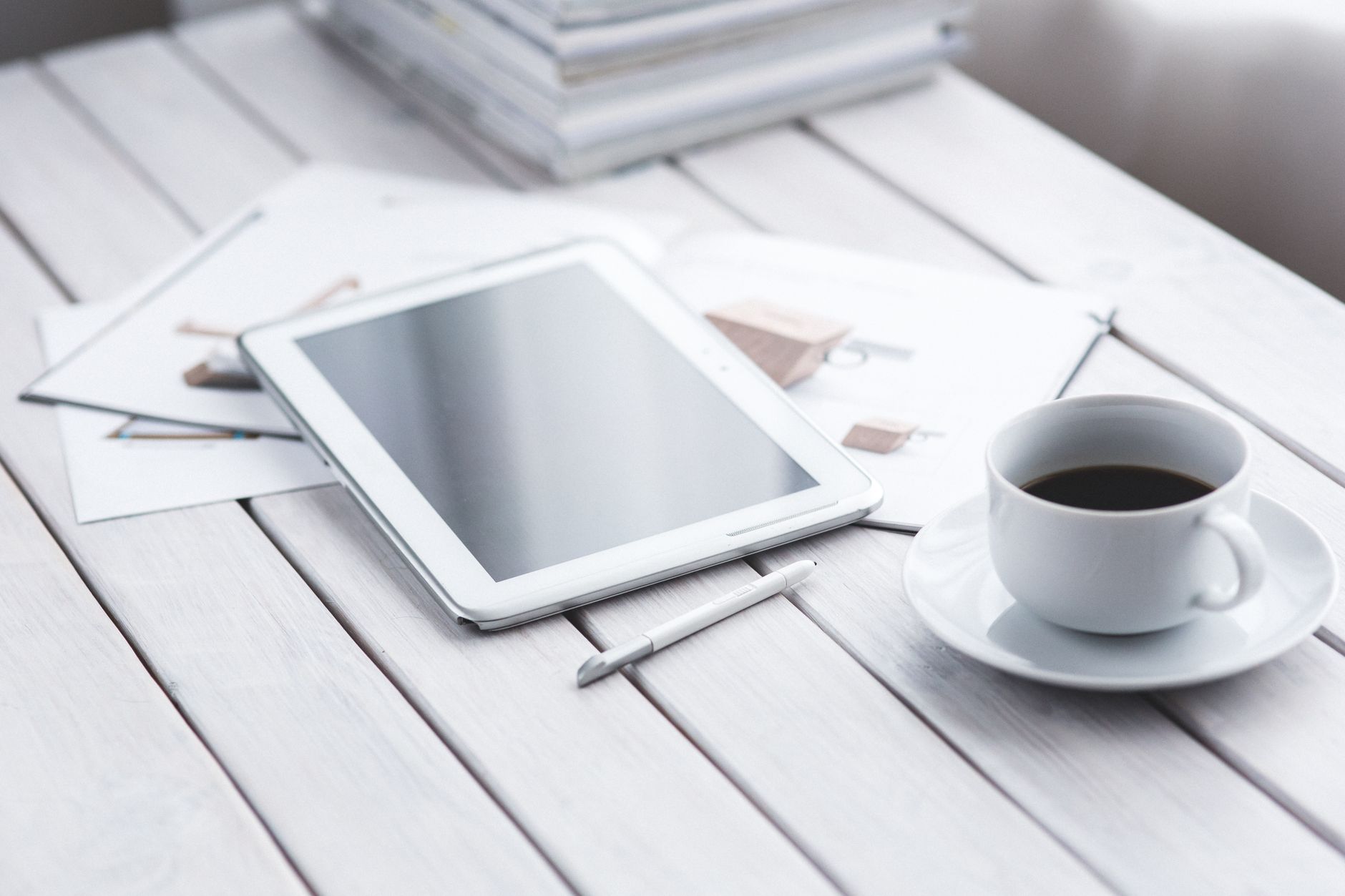 White tablet with stylus and coffee cup on modern office des