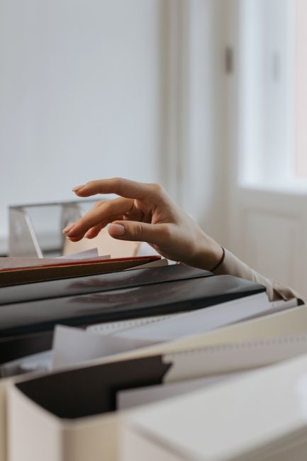 Close-up of a hand reaching into a file drawer in an office,