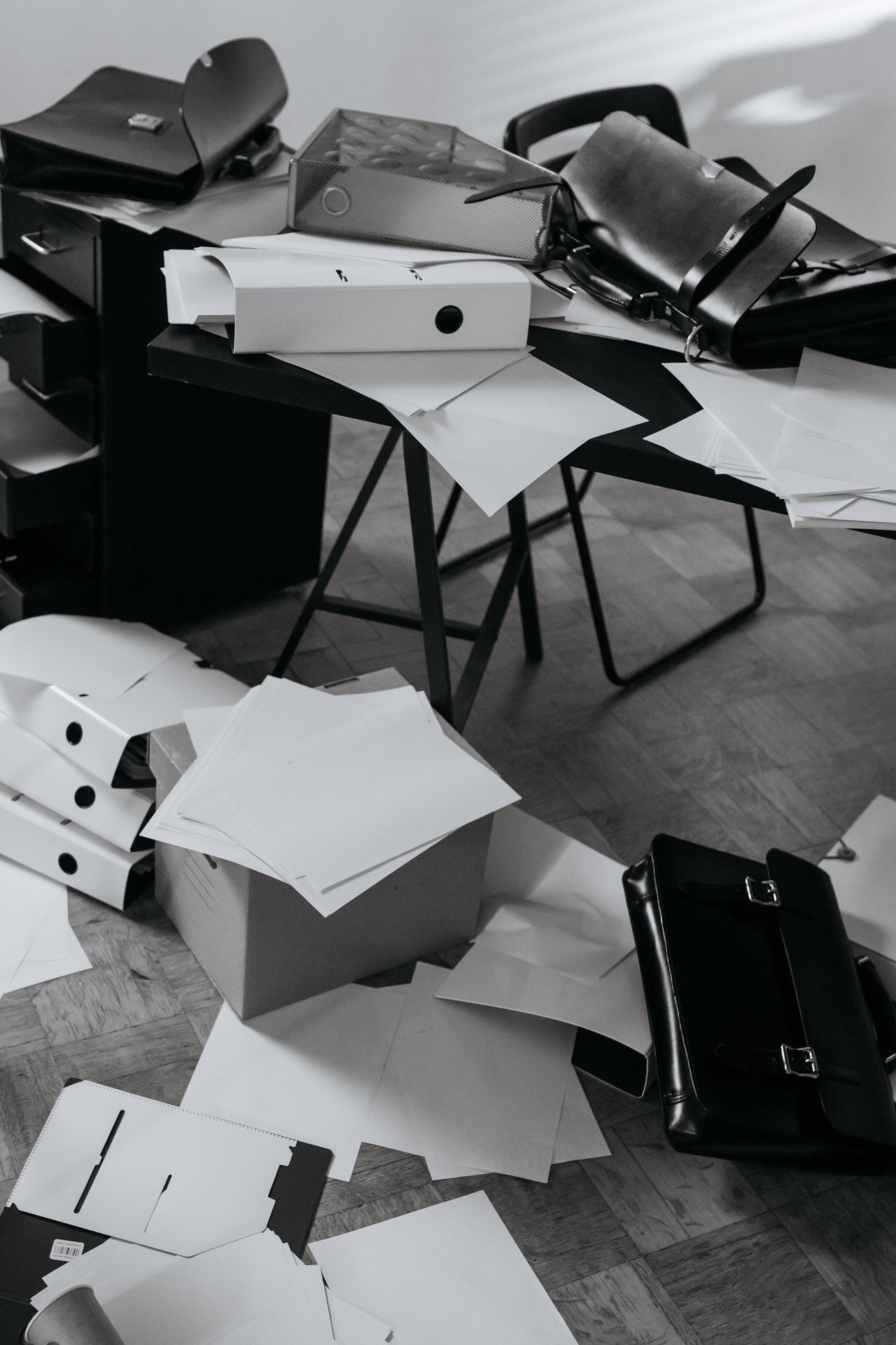 A chaotic office desk covered with scattered papers, folders