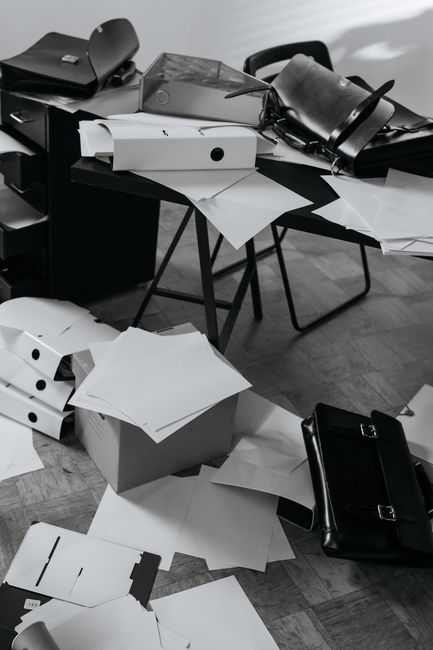 A chaotic office desk covered with scattered papers, folders