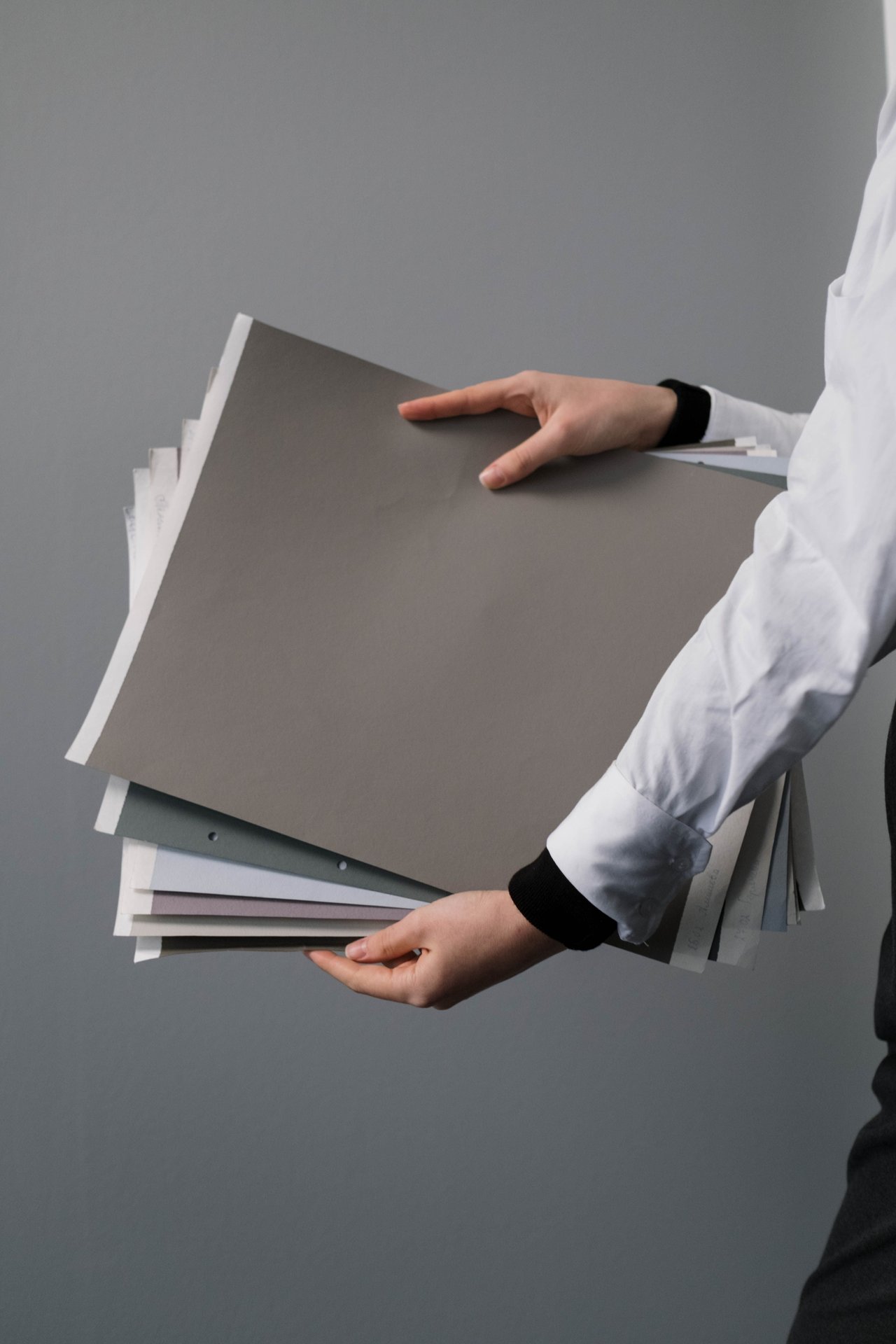 Close-up of hands holding a stack of colored and white paper
