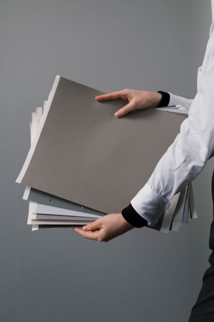 Close-up of hands holding a stack of colored and white paper