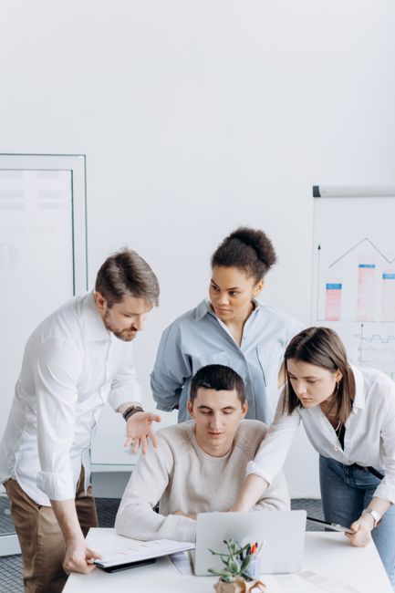 A diverse group of coworkers gathered around a laptop discus