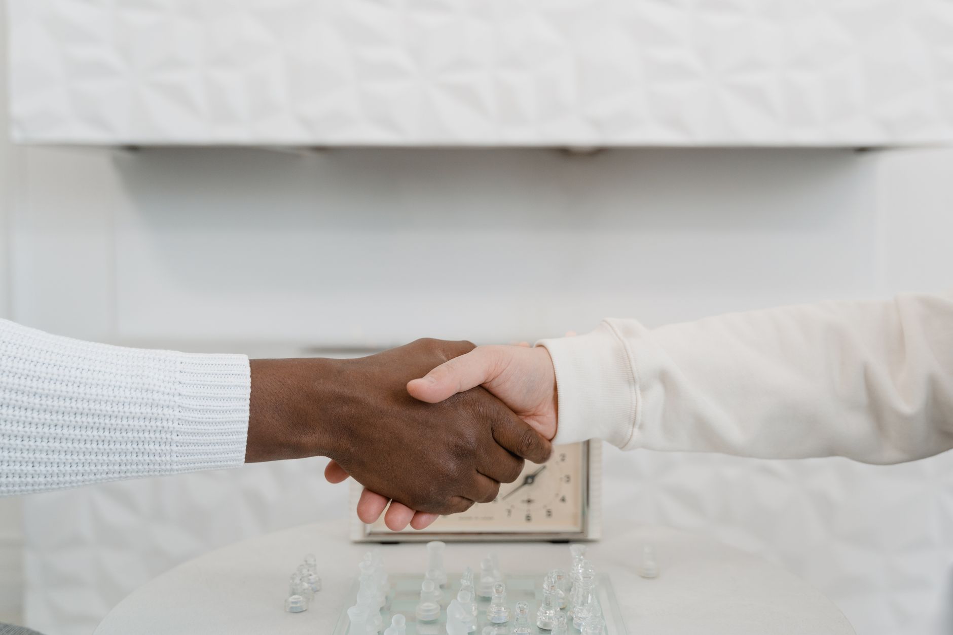 Close-up of an interracial handshake over a chessboard symbo