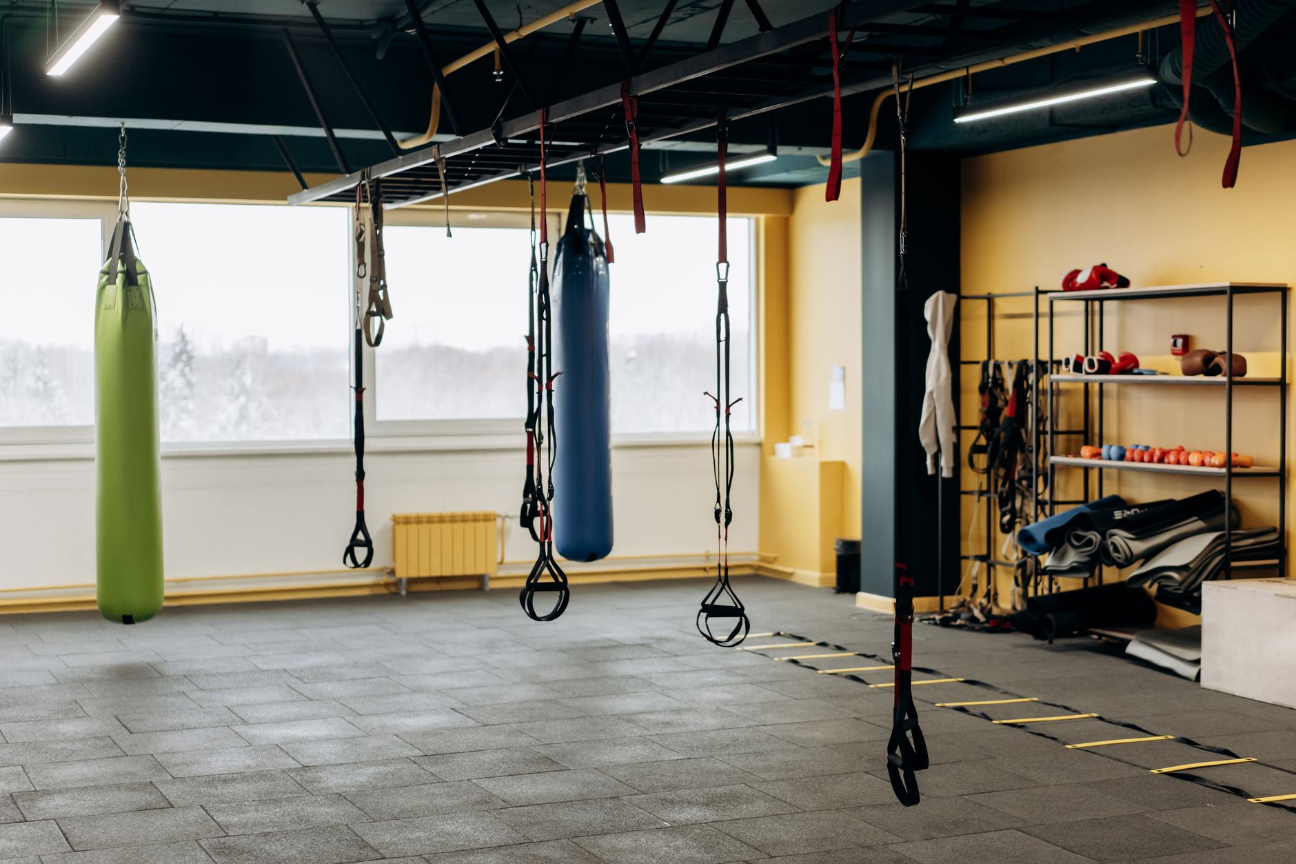 A modern gym with equipment, punching bags, and open space f