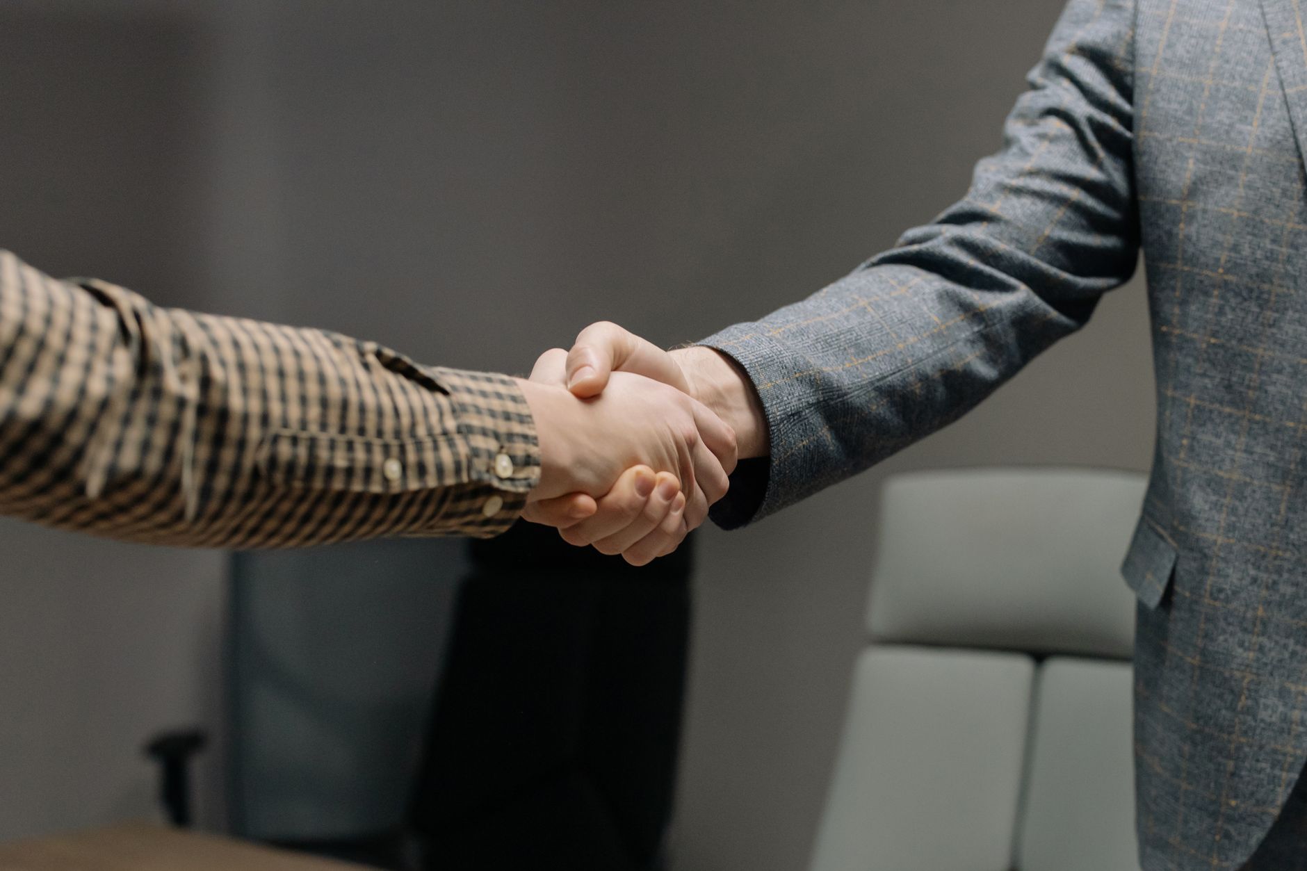 Close-up of two professionals shaking hands in an office, sy