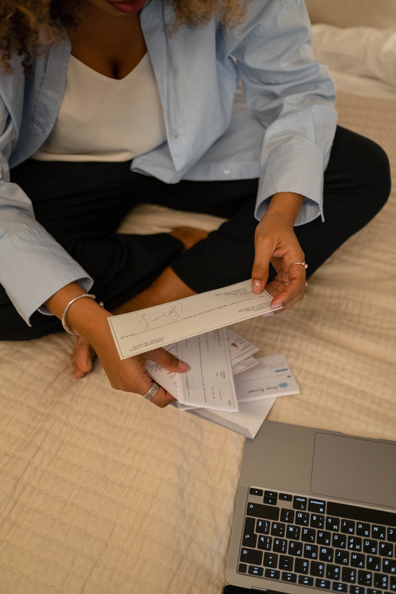 Individual sitting cross-legged examining papers near laptop
