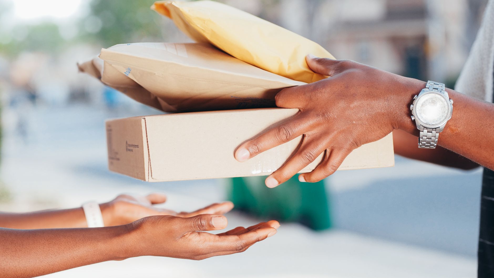 Close-up image of hands exchanging packages outdoors. Repres