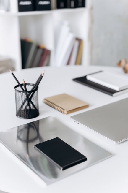 A neat and organized office desk setup with notebooks, penci