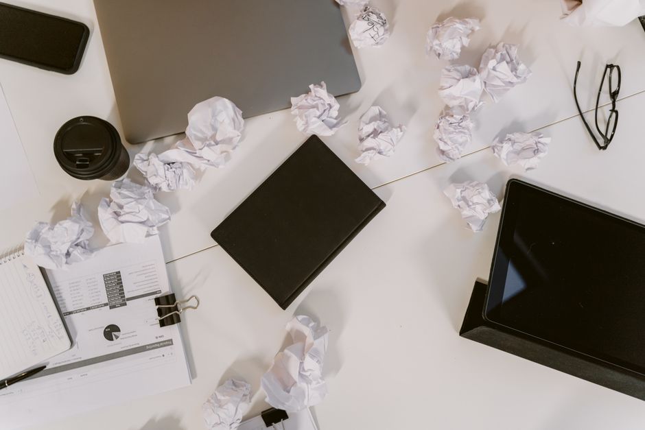 Top view of a cluttered office desk with crumpled papers, la